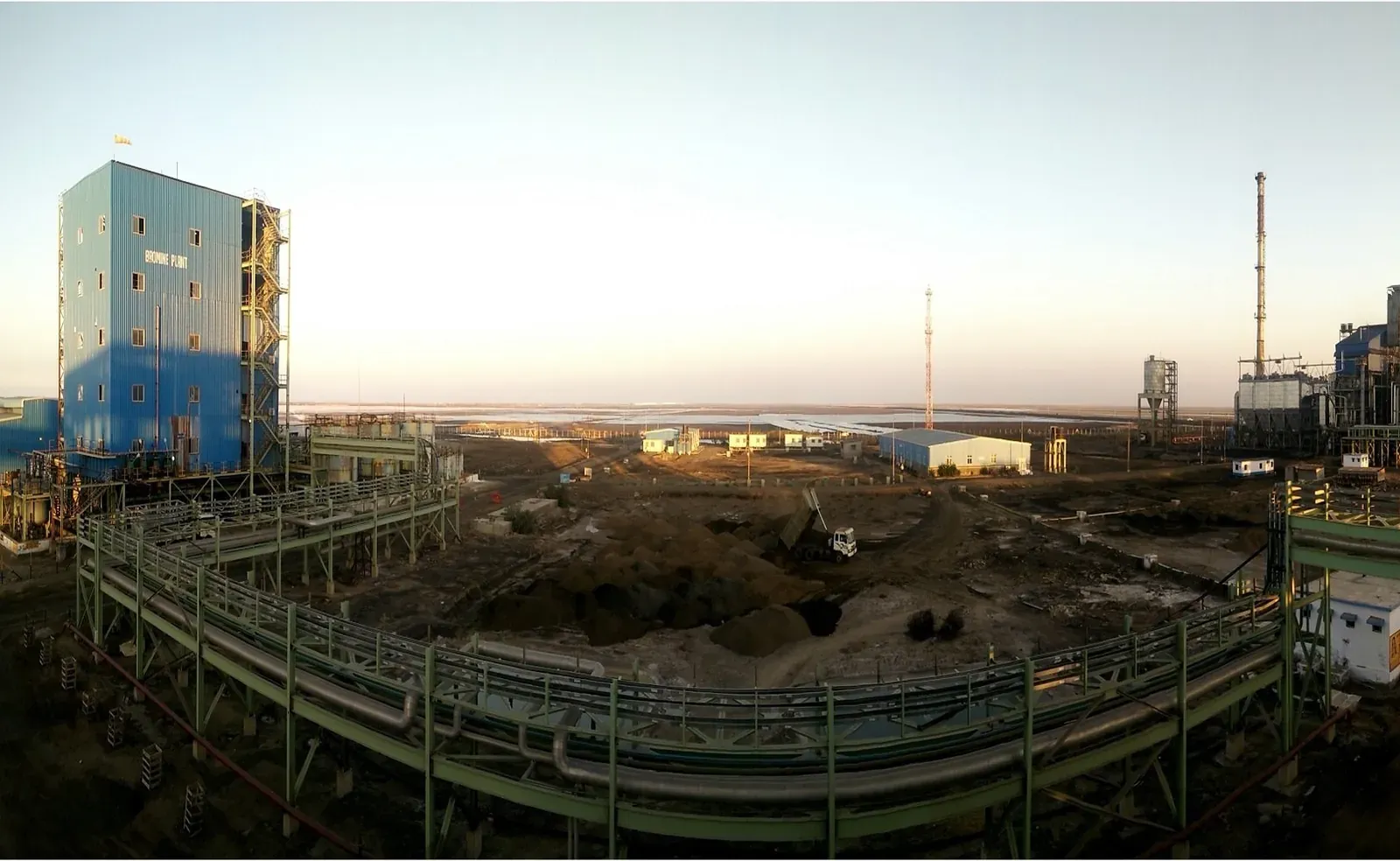 Process plant at dusk: pipe racks, a tower and a chimney