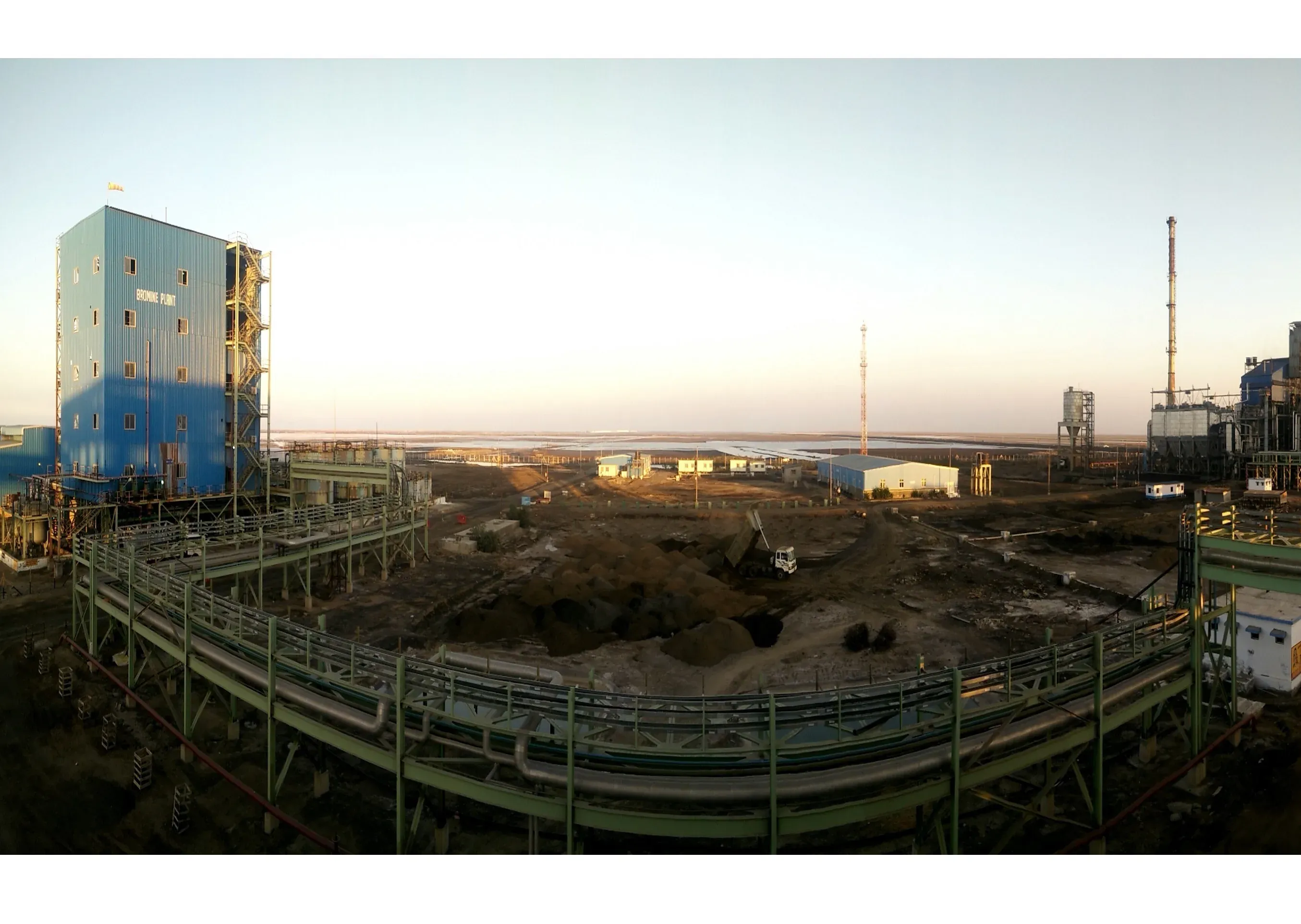 Process plant at dusk: pipe racks, a tower and a chimney